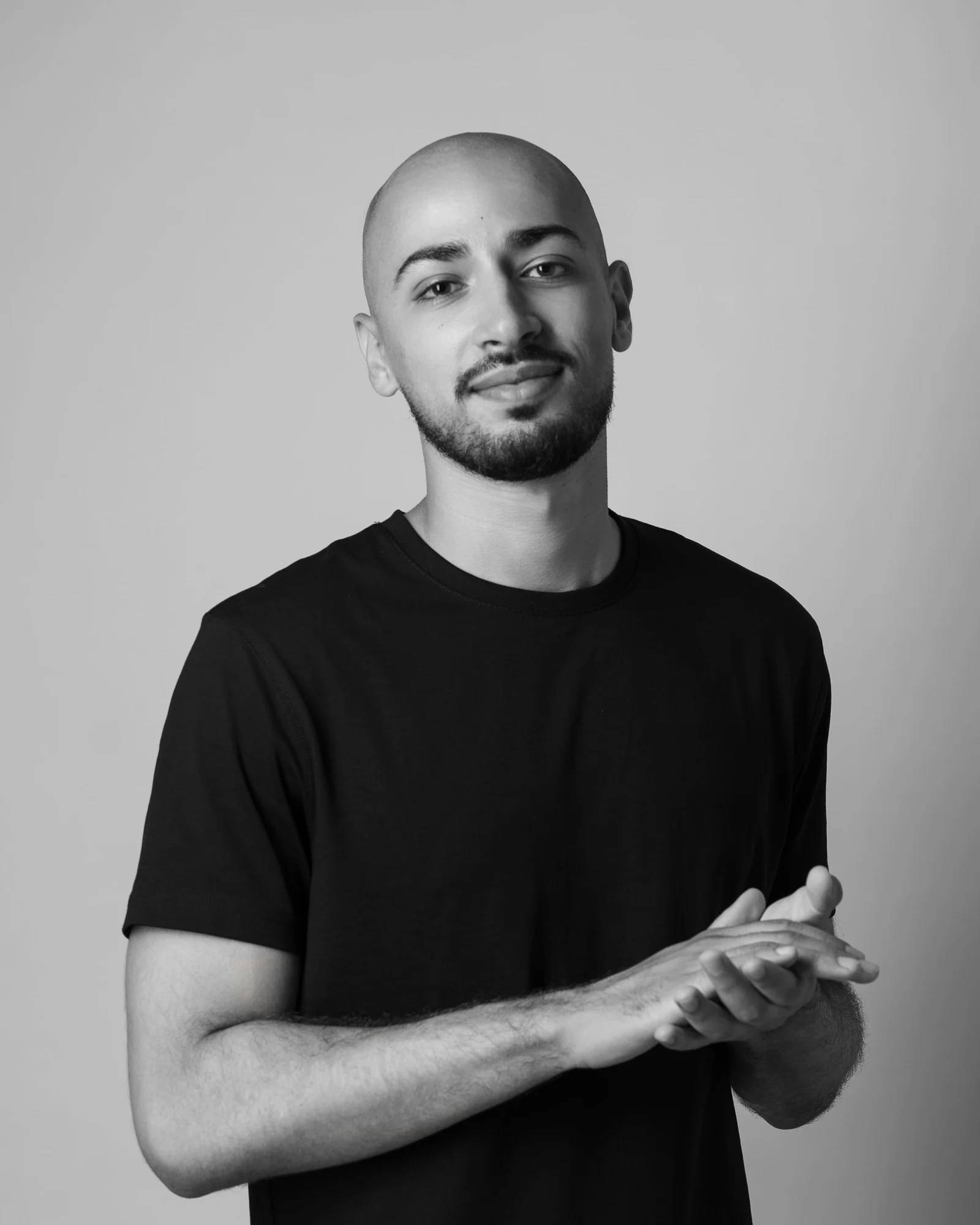 Nacim Meziti, fondateur de Darlia, en tee-shirt noir, souriant, les mains jointes.